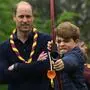 Prinz George mit Pfeil und Bogen, dahinter steht sein Vater Prinz William mit verschränkten Armen