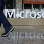 In this April 28, 2015 photo, a man walks past a Microsoft sign set up for the Microsoft BUILD conference at Moscone Center in San Francisco. Microsoft reports quarterly financial results after the market close on Tuesday, July 21, 2015. (AP Photo/Jeff Chiu)