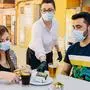 Clients with masks on the terrace of a bar in Spain attended by a waiter with gloves and masks. Social distancing