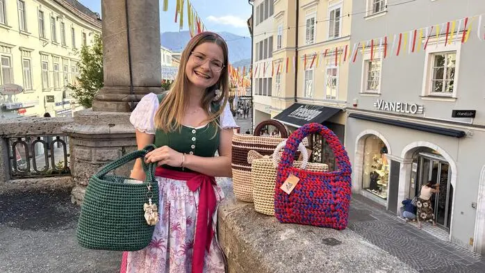 Eine junge Frau im Dirndl mit mehreren gehäkelten Taschen