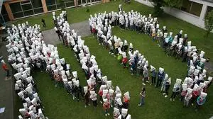 Mit Papiersäcken mit aufgezeichneten Nummern über ihren Köpfen, machten die Schüler auf ihre Situation im Schulinnenhof aufmerksam