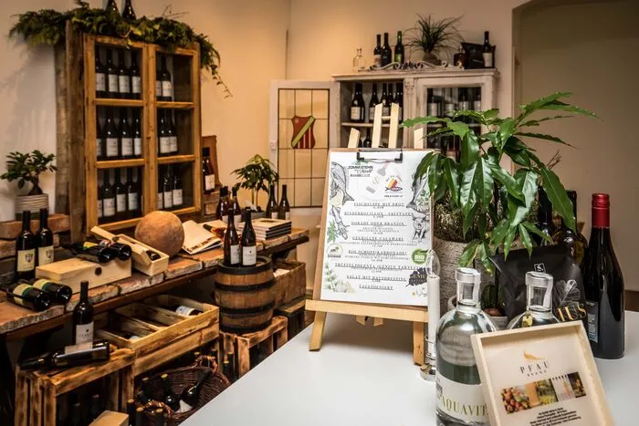 Der Laden unterteilt sich in drei Bereiche, wobei der erste Raum wie eine Vinothek aufgebaut ist, mit Weinfässern und Regalen aus Altholz. Angeboten werden Weine aus dem Vipava-Tal, aus Wolfsberg und aus Jeruzalem.