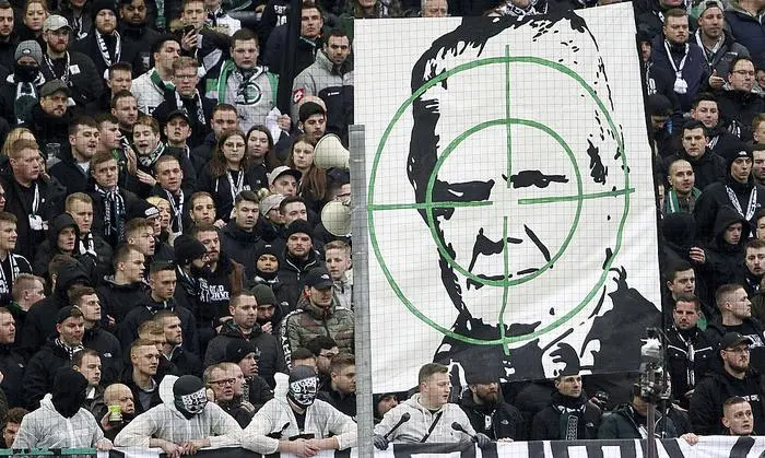 Supporters of Moenchengladbach show a banner with the portrait of Dietmar Hopp during the German Bundesliga soccer match between Borussia Moenchengladbach and TSG Hoffenheim in Moenchengladbach, Germany, Saturday, Feb. 24, 2020. Borussia Mönchengladbach supporters were the center of attention for targeting Hoffenheim’s billionaire backer Dietmar Hopp with crude abusive messages during their sides’ Bundesliga game on Saturday. It led to a suspension in play, but their actions were quickly condemned by fellow fans before the game could be called off. ( Roland Weihrauch/dpa via AP)