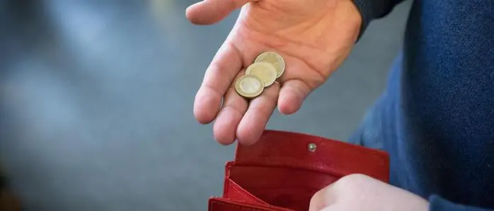 Man sieht eine Person, wie sie Kleingeld in eine Brieftasche gibt | Ein kurioser Prozess wegen fünf Euro Beute konnte am Montag in Klagenfurt nicht stattfinden