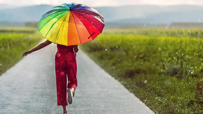 Das Bild zeigt eine Frau, die einen bunten Regenschirm trägt