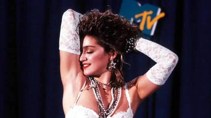 Madonna in einem weißen Bustier mit weißen Spitzenhandschuhen, die bis über die Ellbogen reichen