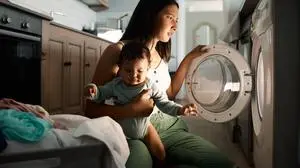 Someone pooped all over our bedding...a mom doing laundry at night with her baby on her arm ,model released, Symbolfoto PUBLICATIONxINxGERxSUIxAUTxONLY Copyright: xZoonar.com/YurixArcursxpeopleimages.comx 19496575 ,model released, Symbolfoto ,property released