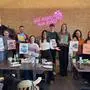 Eine Gruppe von Männern und Frauen in einem Restaurant. Sie halten selbst gemalte Kunstwerke in die Kamera. | Olana Bogachuk (Mitte) mit Workshopteilnehmenden