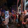 Mehrere Demonstranten mit dem „Palästinensertuch“ Kufiya um den Hals gehängt, stehen vor einer Starbucks-Filiale in Barcelona und bilden davor eine Menschenkette, um Kunden den Zutritt zu verwehren. Eine Frau hält ein Protestschild hoch | Demonstranten riegeln eine Starbucks-Filiale in Barcelona ab
