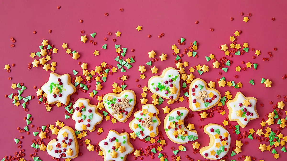 Bunte Plaetzchen zu Weihnachten auf rotem Hintergrund