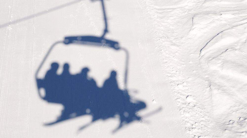 Shadow on the ski slope from the chair elevator with skiers and snowboarders. The problem of opening a ski resort in the COVID-19 pandemic.