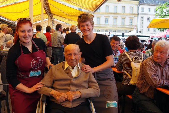 Die Schüler der Klagenfurter Modeschule WI´MO, Julia Schellander und Nicolas Ettlinger, präsentierten die Schürzen, die die Modeschule für Fieranten und Gastronomen kreiert hat. Als Ehrengast nahm Niki Toschkov (Bildmitte) an der Feier teil. Der 99-jährige ehemalige Gärtner war schon am alten Marktplatz am Alten Platz 1938 mit seiner Gärtnerei als Standler vertreten. Er zog 1948 zum neu eröffneten Benediktinermarkt. Sein Enkel, ebenfalls Niki Toschkov, fungierte bei der Feier zum 70er des Benediktinermarktes als Zeremonienmeister. Auch er ist Gärtnermeister und verkauft am Benediktinermarkt.