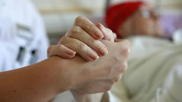 Jemand hält die Hand einer Patientin