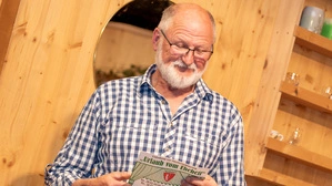 Ein Mann mit grauen Haaren und einer Brille schaut auf einen Theater-Flyer