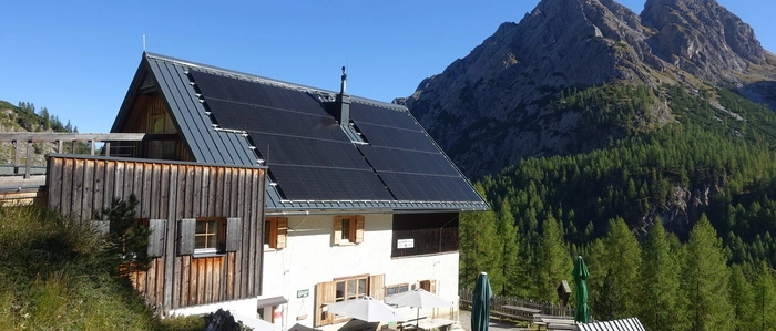 Das Schutzhaus auf der Kerschbaumeralm. Im Hintergrund erhebt sich ein Berggipfel der Lienzer Dolomiten
