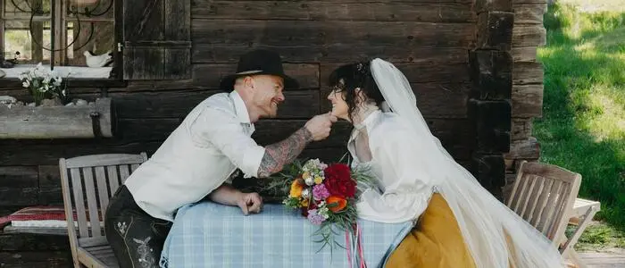 Ein Hochzeitspaar vor einer Almhütte
