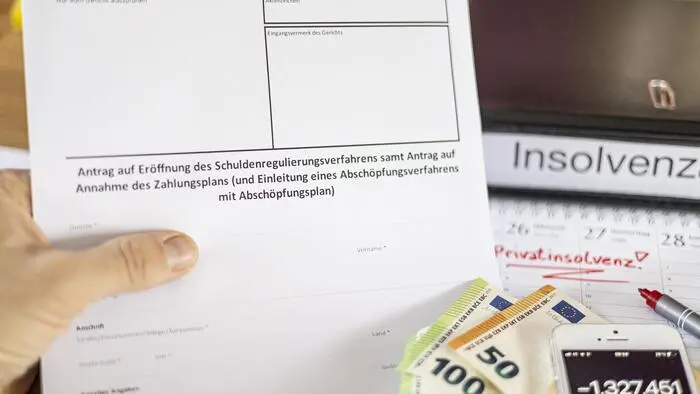 Geld, eine Mappe, ein Handytaschenrechner und ein Antrag liegen auf einem Tisch