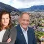 Eine Drohnenaufnahme einer mitteleuropäischen Kleinstadt, davor sind ein Mann und eine Frau in eleganter Business-Kleidung