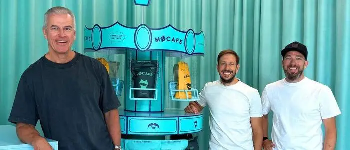 Drei Männer stehen vor einem Kaffee-Regal