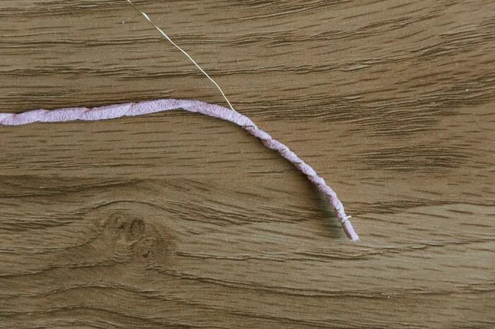 Das erste Stück vom Band mit dem Draht vollständig umwickeln. Am Anfang den Draht ein paar Mal komplett um das Band wickeln. Dann bis zum Ende spiralenförmig das Band mit dem Draht umwickeln. Am Ende wieder fixieren, indem man den Draht ein paar Mal komplett herumwickelt.