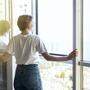 Young woman opening window in living room