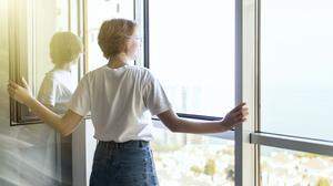 Young woman opening window in living room