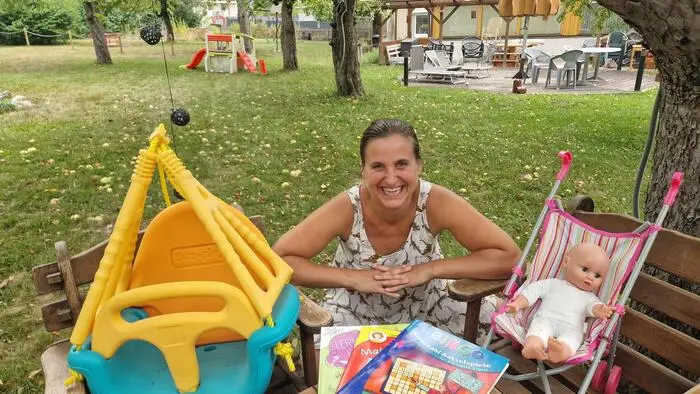 Eine Frau in einem Garten umgeben von Spielsachen
