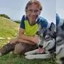 Ein Mann sitzt mit seinem Hund auf einer Almwiese