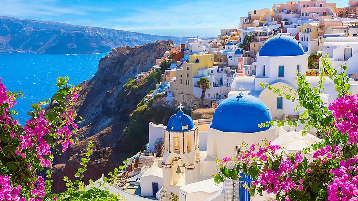 Santorini island, Greece. Oia town traditional white houses and churches with blue domes over the Caldera, Aegean sea.