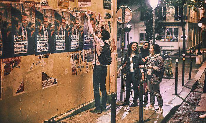 Jugendliche Unterstützer des sozialliberalen Élysée- Kandidaten Emmanuel Macron kleben im nächtlichen Paris Plakate