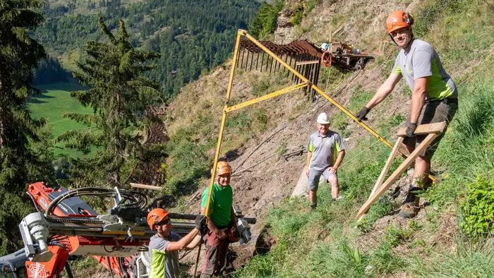 Vier Arbeiter im steilen Gelände