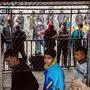 Migrants and refugees, some wearing facemasks for protective measures, queue in a makeshift camp next to the Moria camp on the Greek island of Lesbos on April 2, 2020. - Over 20 coronavirus cases were found in a camp near Athens this week. At the camp of Moria on the island of Lesbos, both doctors and migrants say health precautions are not much help in a facility that is so badly overcrowded. The novel coronavirus could spread faster in overcrowded refugee and displaced persons camps than it has anywhere else so far, warned the International rescue Committee. (Photo by Manolis LAGOUTARIS / AFP)