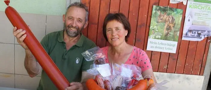 Das Ehepaar hält ihre Produkte in den Händen und lacht in die Kamera