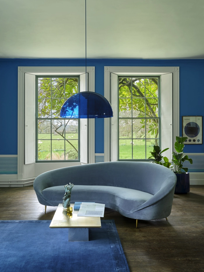 Leuchtend blauer Farbton „Pea Flower Tea“ und die Tapete „Stripe“ in markanten, breiten Streifen von Farrow & Ball bringen Lebendigkeit ins Wohnzimmer
