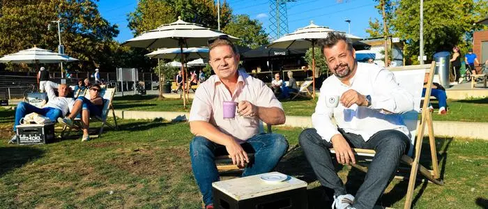 Genießen ihre „Cup of Joy“, gefüllt mit dem Trendgetränk Ube-Latte oder einem richtig guten Cappuccino: Markus Stoffel und Stephan Pensold am Grazer Stadtstrand, wo sie exklusiv vertreten sind