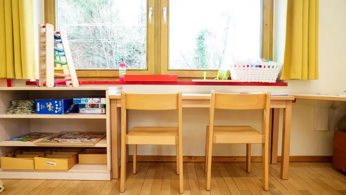 Ein Raum in einem Kindergarten mit einem kleinen Tisch und zwei kleinen Stühlen