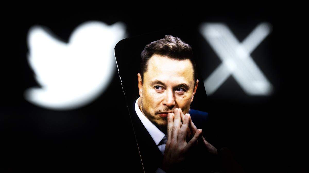 Elon Musk blickt nachdenklich an der Kamera vorbei. Hinter ihm das Twitter-Logo und das X-Logo. | Elon Musk 