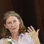 Elke Kahr hält ein Mikrofon in der Hand und gestikuliert mit der anderen. Sie trägt eine weiße Bluse und hat ihre Brille in die Haare gesteckt