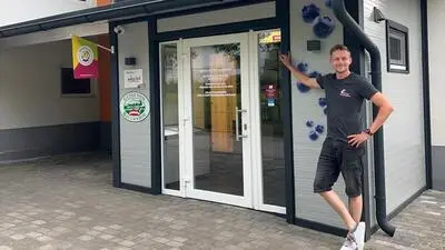 Ein Mann lehnt an einem neuen Hofladen