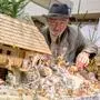 Ein älterer Herr mit weißem Bart und Hut steht hinter einer traditionellen Krippe, welche die Geburt von Jesus darstellt | Heinz Eichler ist Obmann der Krippenfreunde Feldkirchen