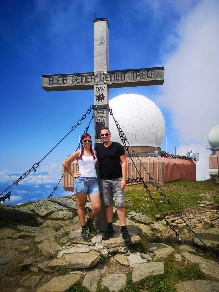 Jennifer und Alexander sind gerne auf den Bergen unterwegs. Hier stehen sie vor dem Gipfelkreuz am Großen Speikkogel an der Grenze zu Kärnten