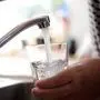 Frisches Leitungswasser fließt sprudelnd aus einem Wasserhahn in ein Glas