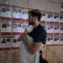 Ein Mann mit Baby schaut auf eine Wand, auf der die Fotos der von der Hamas verschleppten Israelis hängen