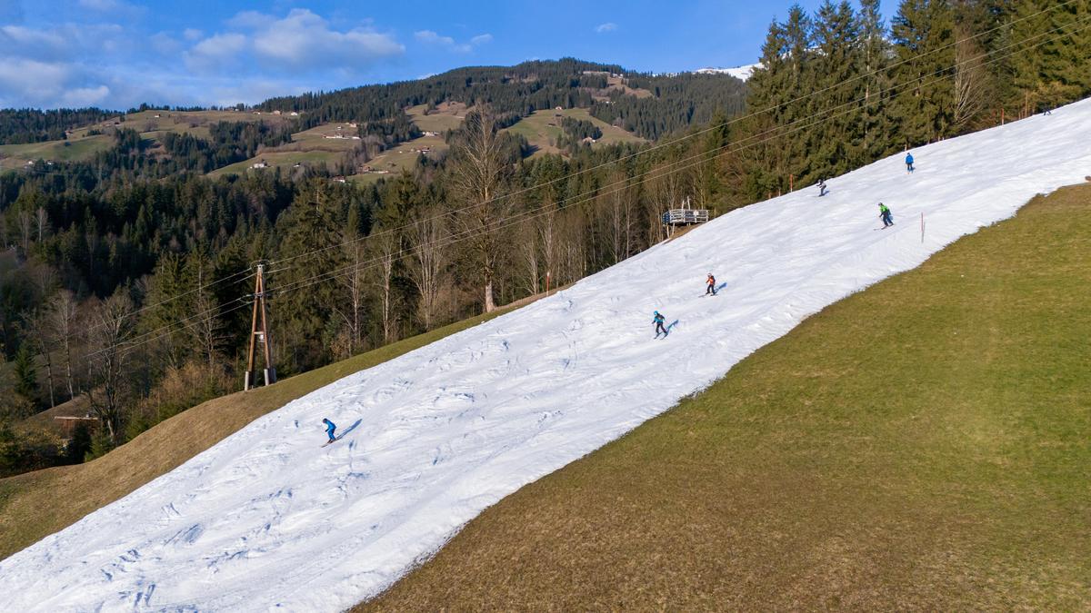 Ein Bild, das man im Februar 2024 öfter sah: Nur noch ein schmales Schneeband dient als Skipiste, wie hier von der Hohen Salve nach Hopfgarten im Brixental