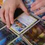 Eine Kinderhand greift zu einer Pokémon-Sammelkarte, die sich in einem Album befindet. | Seltene Pokémon-Sammelkarten können pro Stück mehrere tausend Euro wert sein (Symbolbild)