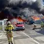 Mehrere Feuerwehrleute löschen einen Brand in einem Entsorgungsbetrieb