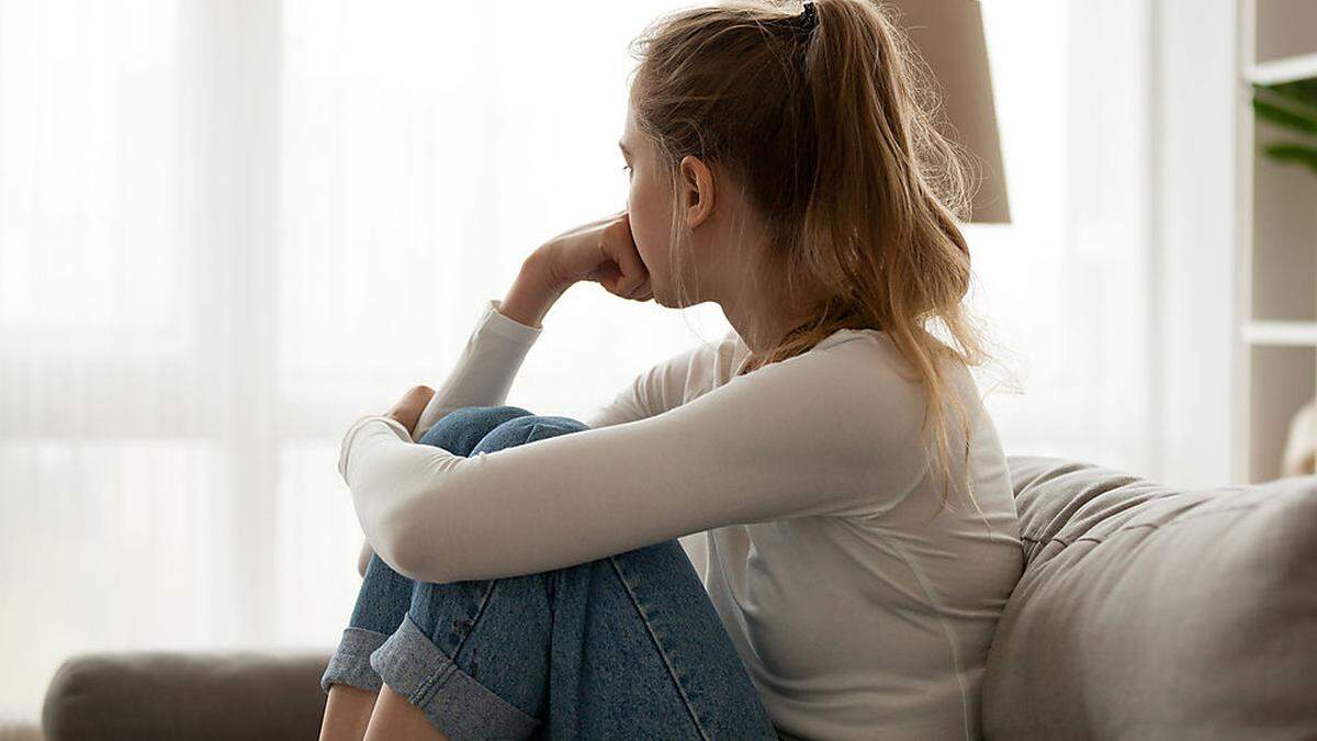 Upset woman sitting on couch alone at home