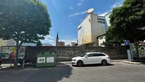Blick auf eine Straße und eine Mauer, dahinter eine Kirche und ein großes Gebäude mit der Aufschrift „Villacher“