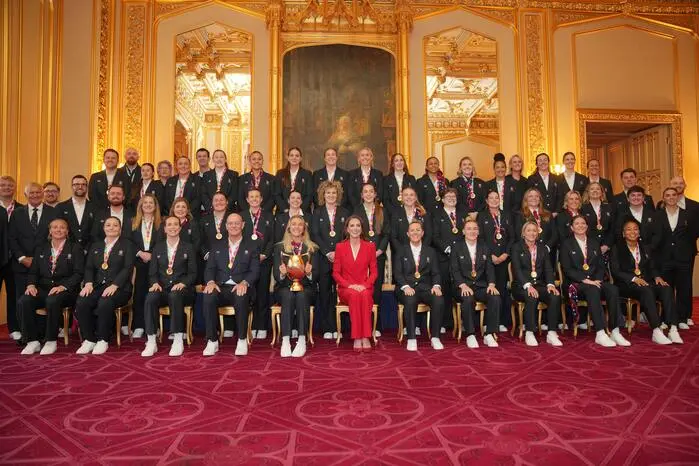 Nicht zu übersehen: Mit ihrem feuerroten Hosenanzug stach Kate beim Foto mit dem Team hervor.