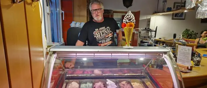 Ein älterer Herr steht hinter einer Eisvitrine